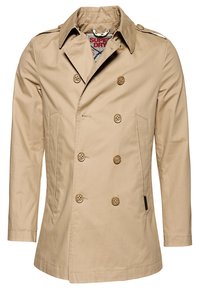 Cappotto beige doppiopetto con colletto strutturato, dettagli con bottoni e tasche laterali. Realizzato in tessuto morbido e leggero.