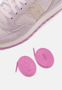 Sneaker lilla chiaro con una tomaia in sintetico liscio e dettagli in camoscio. Include due lacci rotondi rosa accanto alla scarpa.