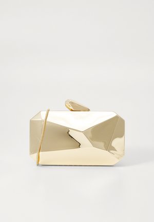Glanzende gouden geometrische clutch met een klein sluitinkje bovenaan en een dunne kettingriem op een effen lichte achtergrond.