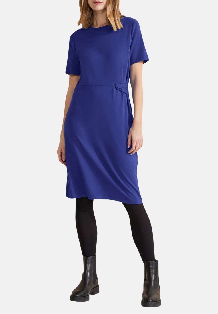 Robe bleu royal midi avec des manches courtes, détail de ceinture à la taille, fabriquée en tissu doux, associée à des bottines noires et des collants.