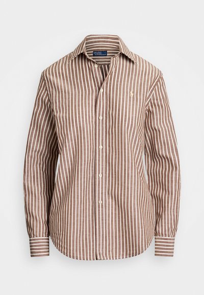 Raidallinen nappikauluspaita ruskeassa ja kerma väriissä, jossa on klassinen kaulus ja pitkät hihat, rintalogolla ja kaarevalla helmalla.