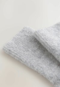Grå, fluffy tekstil med en blød, struktureret overflade, der har en foldet kant. Stoffet ser varmt og hyggeligt ud.