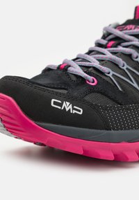 Svart atletisk sko med rosa detaljer, med en teksturert overflate, grå såle og mesh-paneler for pusteevne. CMP-logo synlig.