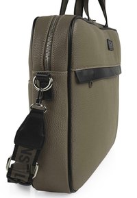 Bolso de cuero caqui con una superficie texturizada, ribetes negros, asas superiores y una correa ajustable con un acento de la marca. Cierre con cremallera.