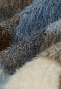 Tkanina o miękkiej, puszystej fakturze w odcieniach brązu, beżu i niebieskiego, z różnorodnymi wzorami i wielowarstwowym wyglądem.