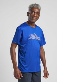 T-shirt de sport bleu à manches courtes en matériau léger, présentant un design de chaîne de montagnes en gris sur la zone de la poitrine.