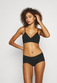 Bralette nera con spalline sottili abbinata a shorts neri coordinati. Tessuto morbido, design minimalista, che mette in risalto la forma del corpo.
