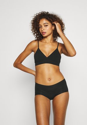 Černý bralet s tenkými ramínky v kombinaci s odpovídajícími černými boyshorts. Hladká látka, minimalistický design, který zvýrazňuje tvar těla.