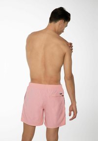 Lichtroze zwembroek met een elastische tailleband en een achterzak, met een gladde textuur en een minimalistisch ontwerp.