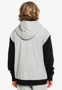 Hoodie met een grijze achterkant en zwarte mouwen. Heeft een ruime capuchon en ribgebreide manchetten, gemaakt van zacht, textuurstof.