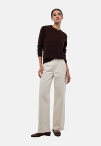 Pull marron, pantalon large crème et chaussures plates marron. Tissu en tricot texturé sur le pull, style classique en denim avec poches avant.