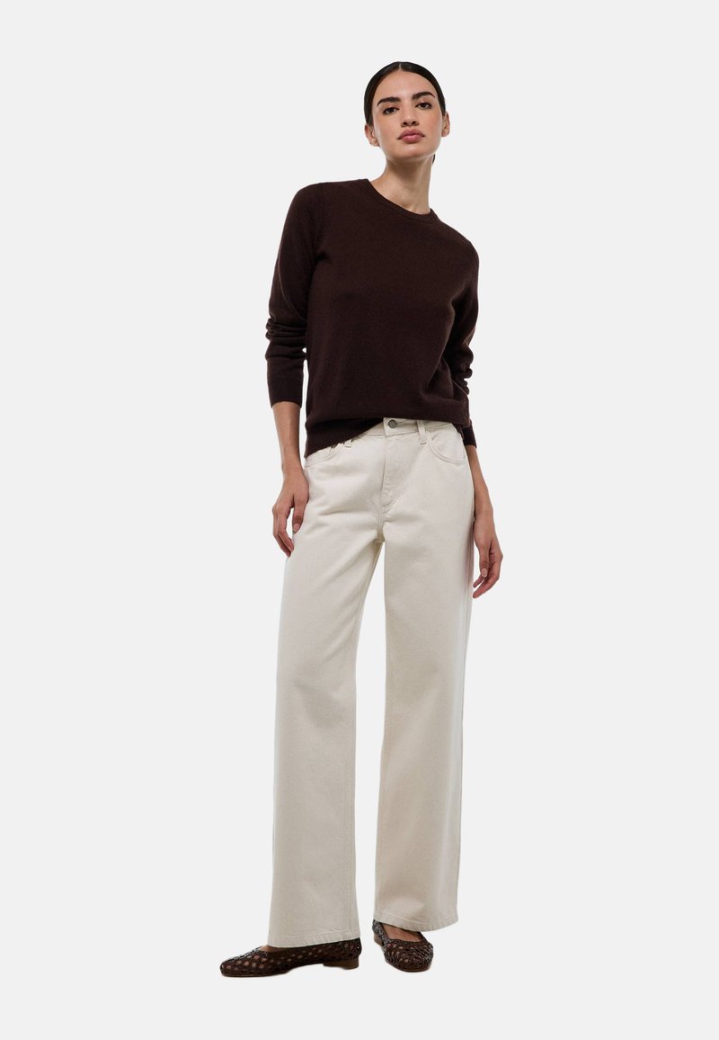 Pull marron, pantalon large crème et chaussures plates marron. Tissu en tricot texturé sur le pull, style classique en denim avec poches avant.