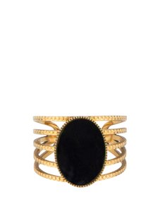 Gouden metalen armband met een ovale zwarte steen in het midden, omgeven door meerdere golvende banden en textuuraccenten rond de randen.