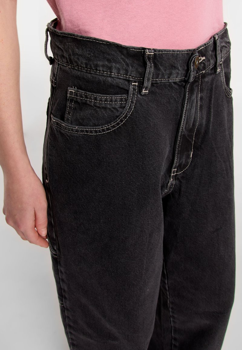 Jeans in denim nero con vita alta, grandi tasche laterali e dettagli di cucitura bianca. Il tessuto ha una texture liscia.
