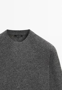 Maglione di lana grigia con scollo tondo, tessuto strutturato e etichetta visibile all'interno del colletto. Design semplice e classico.