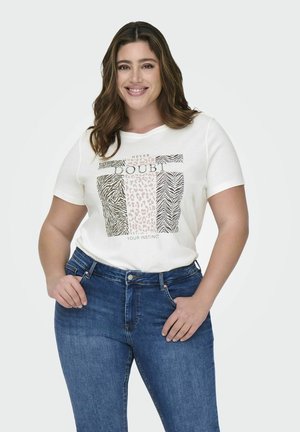 T-shirt blanc à manches courtes avec un design graphique présentant des motifs de zèbre et de léopard, associé à un jean en denim bleu.