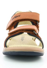 Sandalias de cuero marrón con dos correas ajustables, plantilla de un suavizante beige y suela curvada azul marino. Logo visible en la correa. Talla 25.