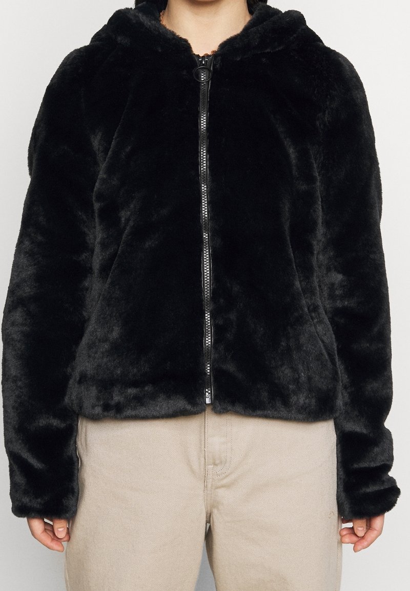 Svart fuskpäls zip-up hoodie med huva, med en silverfärgad dragkedja och lång ärm. Mjuk textur och något kortare passform.