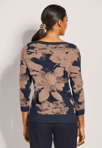 Strickpullover mit floralen Muster in Beige auf dunklem Marinehintergrund. Mit 3/4-Ärmeln und weitem Ausschnitt. Strukturiertes Finish.
