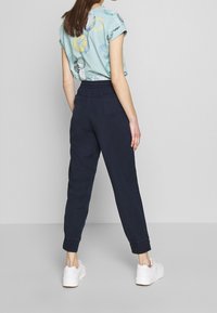 Lichtblauw T-shirt met korte mouwen met meerkleurige cirkelpatronen, gecombineerd met marineblauwe joggingsbroek met elastische boorden en een relaxte pasvorm.