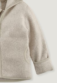 Hellbeige Fleecejacke mit einer strukturierten Oberfläche, Reißverschluss und zwei seitlichen Taschen. Verfügt über eine Kapuze und weiche, gerippte Bündchen.