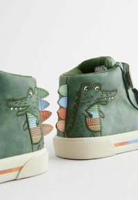 Grüne Leder-Hochschuhe mit einem Krokodil-Design, verziert mit mehrfarbigen Stoffspitzen entlang der Ferse und einer strukturierten Gummisohle.