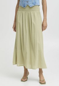 Jupe maxi fluide vert clair en tissu doux avec une taille smockée. Présente un design froncé pour un ajustement décontracté.