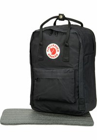Svart Fjällräven Kanken ryggsekk laget av slitesterkt stoff, med to håndtak oppe, en frontlomme og en grå polstret bunn.