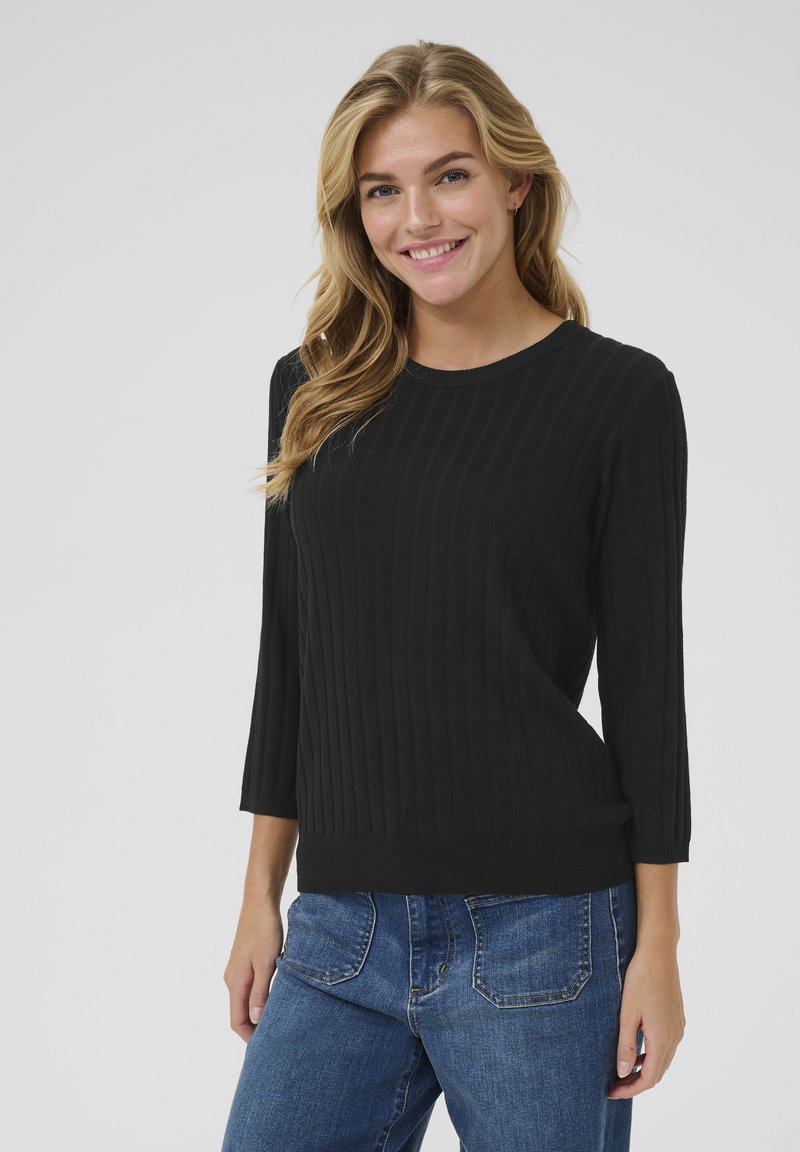 Pull en tricot côtelé noir avec un col rond et des manches trois-quarts, associé à un jean en denim bleu. Texture lisse, design ajusté.