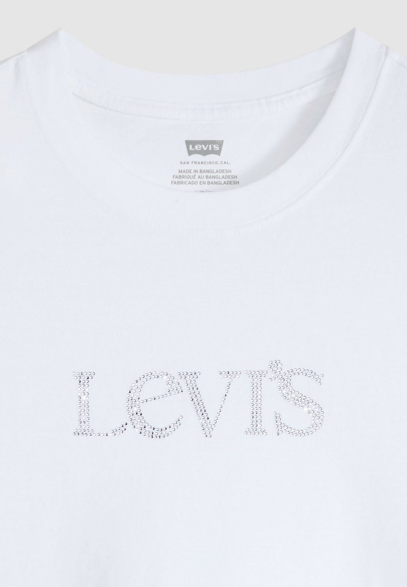 T-shirt blanc Levi's avec des clous formant le logo sur le devant et une étiquette imprimée à l'intérieur du col indiquant qu'il est fabriqué au Bangladesh.