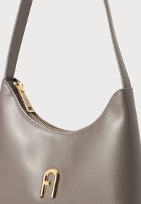 Bolsa de mão cinza em pele com um topo curvo, detalhes em fecho dourado e um logotipo em relevo. Textura suave com uma alça única.