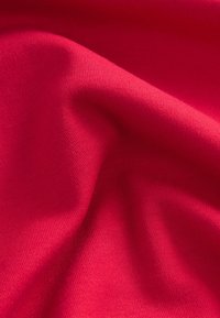 Rødt strækstof med en glat tekstur og fin ribstruktur, der falder blødt med blide folder. Farven er ensartet og livlig.