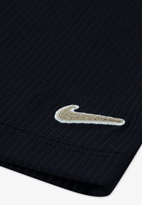 Námornícka rebrovaná tkanina s textúrovaným povrchom a výrazným vyšitým zlatým logom Nike v pravom dolnom rohu.