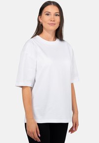 T-shirt bianca in cotone con maniche corte, vestibilità comoda, scollo rotondo, texture liscia e senza motivi o loghi visibili.