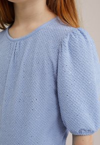 Light blue textured dress with puffed sleeves. Fabric features a honeycomb pattern and small silver sequins for added detail.