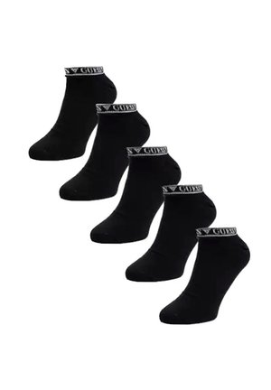 Cinq paires de chaussettes noires à la cheville avec une bordure blanche marquée "GUESS" autour des poignets, disposées en ligne diagonale sur un fond blanc.
