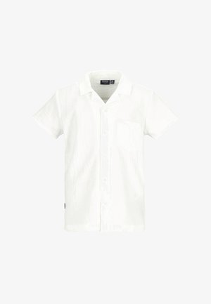 Biała koszula z krótkim rękawem z kieszonką na piersi, w połączeniu z jasnoniebieskimi, luźnymi dżinsami i beżowymi, plecionymi sandałami na grubej podeszwie.