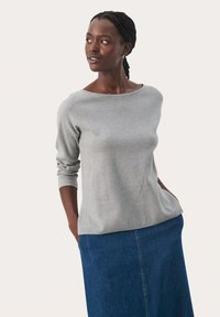 Hallhalli hallïng, millel on lai kaelus, pehme tekstuur ja vabalt langev lõige, on kombineeritud sinise denim seeliku juurde.