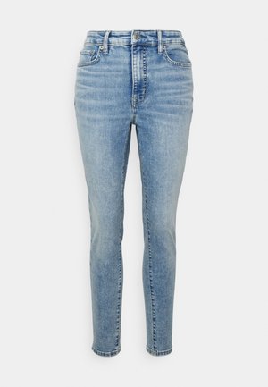 Jean skinny bleu clair taille haute avec fermeture à boutons et zip à l'avant, poches avant et arrière, présenté sur un fond blanc.