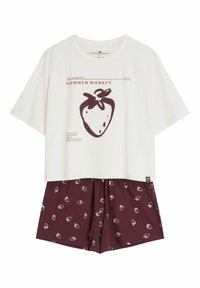 Biała koszula z krótkim rękawem z dużym brązowym nadrukiem truskawki i tekstem, zestawiona z brązowymi szortami w małe białe truskawkowe wzory.