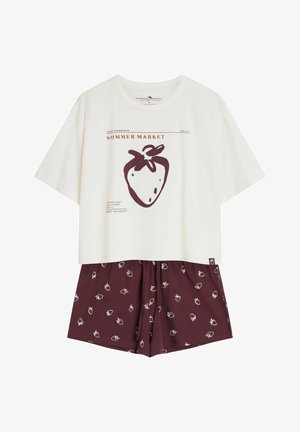 Biała koszula z krótkim rękawem z dużym brązowym nadrukiem truskawki i tekstem, zestawiona z brązowymi szortami w małe białe truskawkowe wzory.