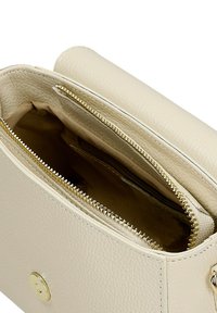 Beige leren handtas met een gestructureerde afwerking, voorzien van een gouden rits en hardware, twee compartimenten en een magnetische drukknoopsluiting.