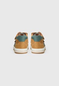 Bottes montantes en daim marron avec des accents en teal, semelle intermédiaire blanche et semelle en caoutchouc. Comprend un talon texturé et une sangle à boucle et scratch.