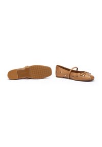 Chaussures plates marron avec un bout arrondi, dotées d'ouvertures découpées, d'un nœud à l'avant et d'une fine sangle sur le cou-de-pied. Semelle en caoutchouc.