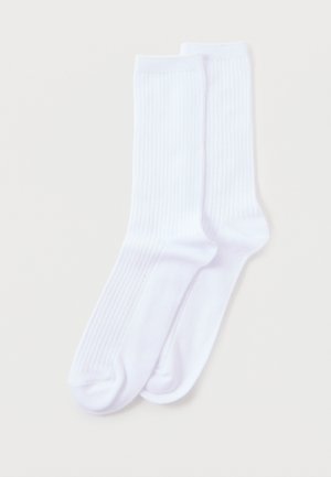 Paar schlichte weiße, gerippte Knöchelsocken, flach auf einem hellen Hintergrund ausgelegt.