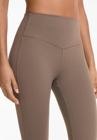 Hochtaillierte Leggings in Taupe, aus glattem, dehnbarem Material. Mit flachen Nähten und einem figurbetonten Design.