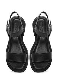 Sandalias de cuero negro con parte posterior abierta, que cuentan con tiras anchas a lo largo del pie y una hebilla ajustable en el tobillo. Acabado suave y diseño minimalista.