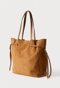 Geantă tote din suede maro cu curele din piele bej, textură moale, partea de sus deschisă și șnururi pe lateral pentru închidere. Prezintă detalii cu cusături în contrast.