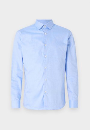 Chemise bleu clair à manches longues, avec un col pointu et des boutons blancs. Présente un col intérieur à motifs. Texture de tissu lisse.