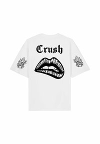 T-shirt blanc avec texte gothique noir "Crush" au-dessus de lèvres brillantes mordillant la lèvre inférieure, avec des motifs de dés en flammes sur les deux manches.